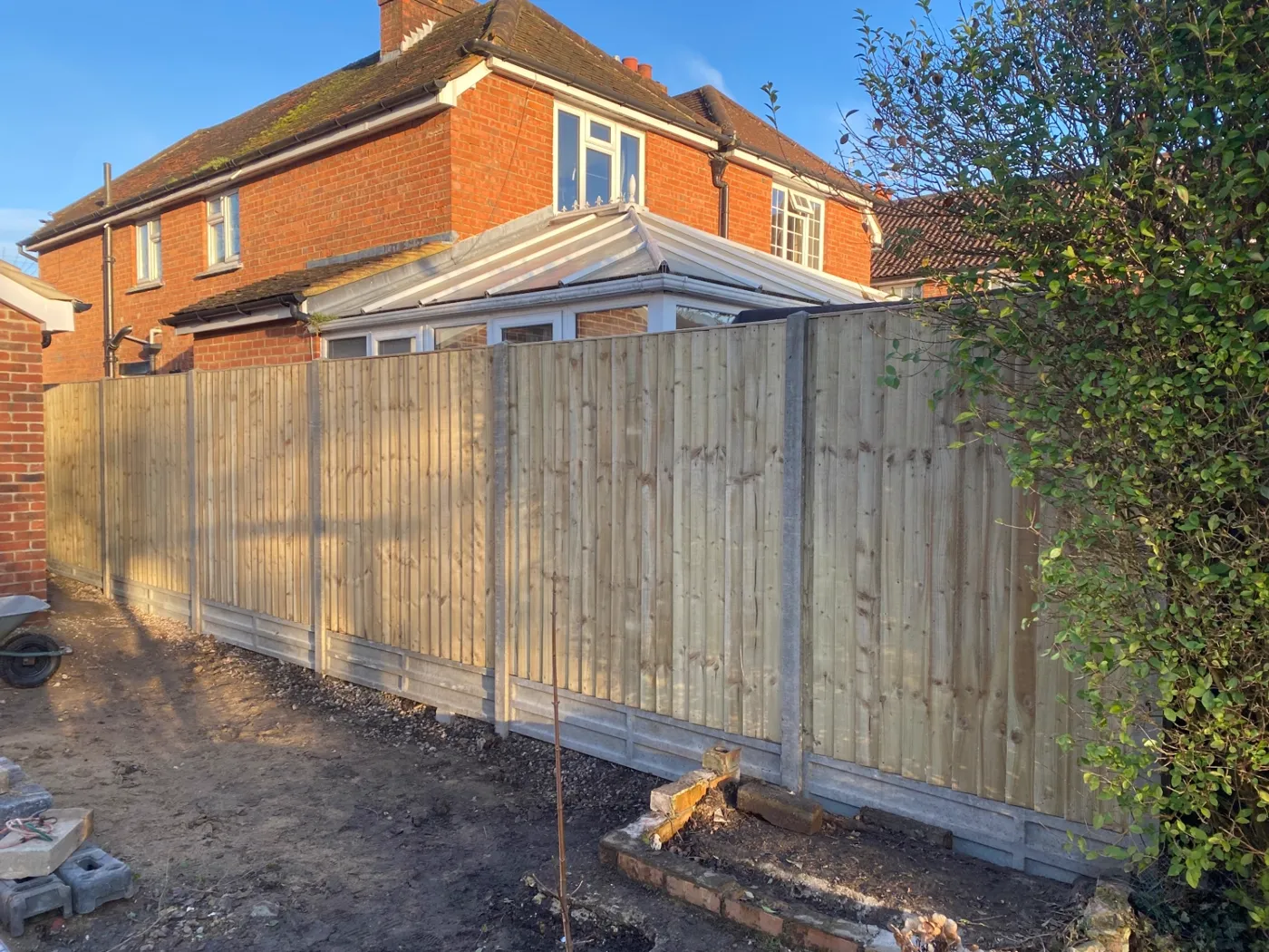 New closeboard fence installation with concrete posts and gravel boards beside a house